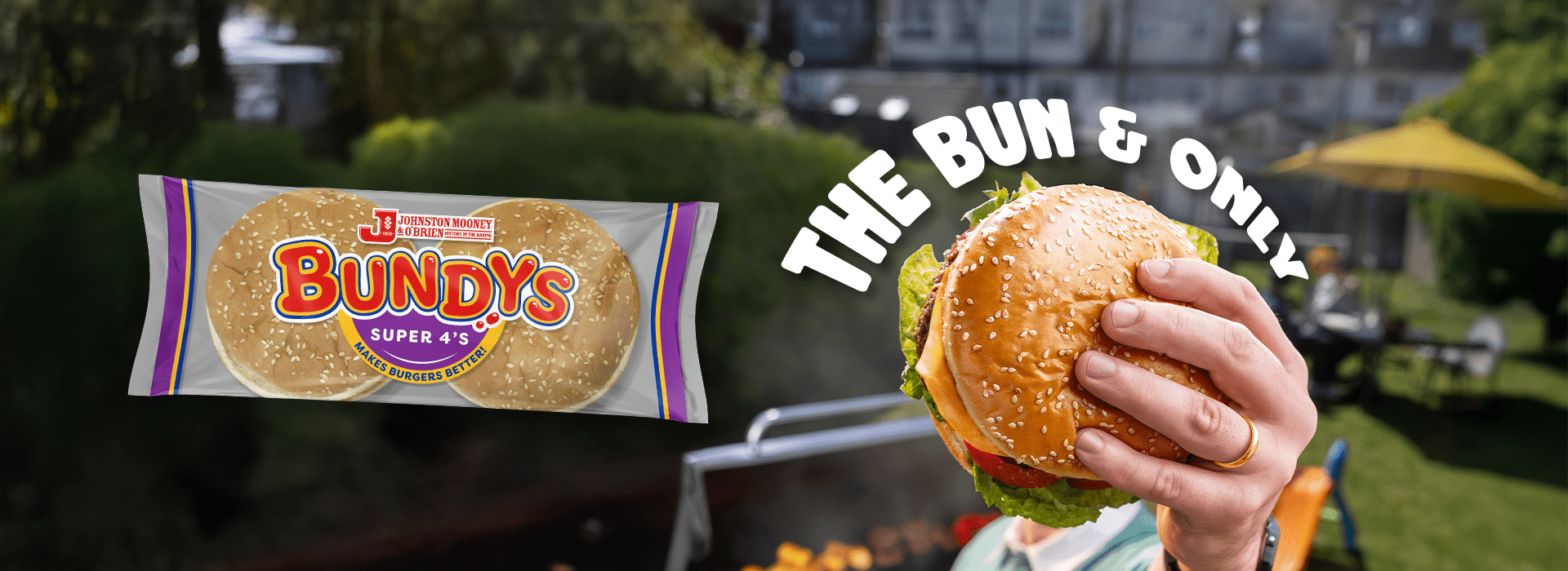 Man holding a burger in a Bundys bun in the air, with the text above the Burger that says The Bun & Only. A pack of Bundys Super 4's appears beside the hand